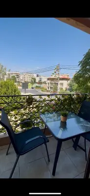 a table and a chair on a balcony with a view at Glow and Grace in Abdoun Best location in Amman