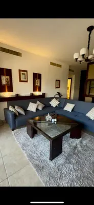 a living room with a blue couch and a coffee table at Glow and Grace in Abdoun Best location in Amman