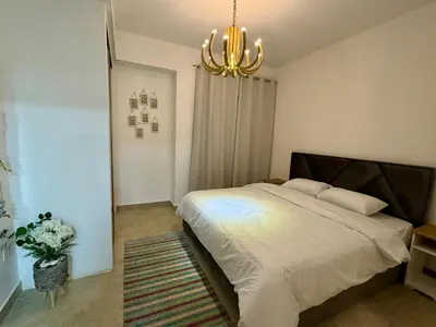 a bedroom with a large bed and a chandelier at Loom & Light In the best location in Abdoun Amman in Amman