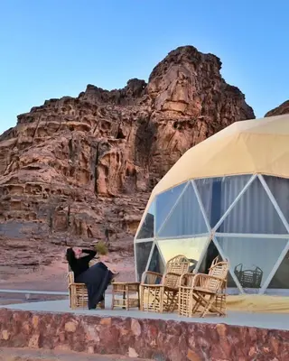 a woman sitting in a chair in front of a tent at RUM MAGIC BUBBLE lUXURY CAMP in Wadi Rum