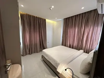 a bedroom with a white bed and pink curtains at Masaken Hotel Apartment in Amman