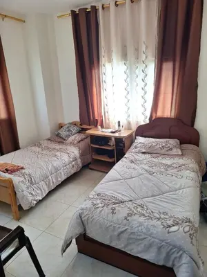 a bedroom with two beds and a desk and a window at الشقة الفاخرة Luxerios apartment in 0MM Nowwara in Amman