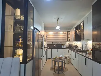 a kitchen with white cabinets and a table in it at شقة مميزة in Rujm Maghghijhah