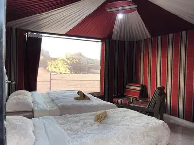 two beds in a room with a large window at Rotana Wadi Rum in Wadi Rum