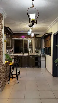 a kitchen with wooden cabinets and a bar with stools at Cozy and well-located 2 bedroom flat near a mall in Amman
