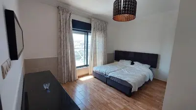 a bedroom with a bed and a table and a window at Nice cozy place in Amman