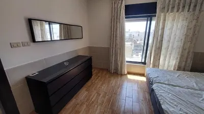 a bedroom with a bed and a dresser and a window at Nice cozy place in Amman