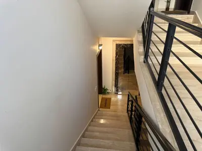 a staircase in a house with white walls and wooden floors at The view in Māḩiş