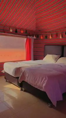 a bedroom with a large bed with a red wall at Crescent Camp & Tours in Wadi Rum