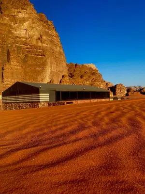 a building in a desert with a large rock at Crescent Camp & Tours in Wadi Rum
