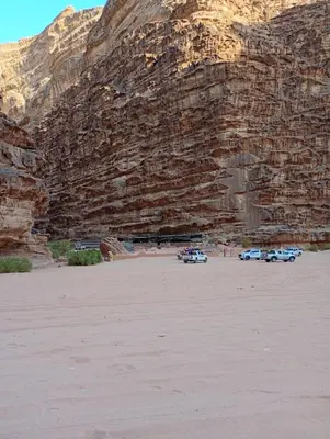 three cars parked in front of a rocky mountain at Shadow of Rum camp in Wadi Rum