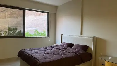 a bedroom with a bed with a window at Flow - Al Raha Village in Aqaba