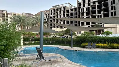 a swimming pool with two chairs and umbrellas at Flow - Al Raha Village in Aqaba