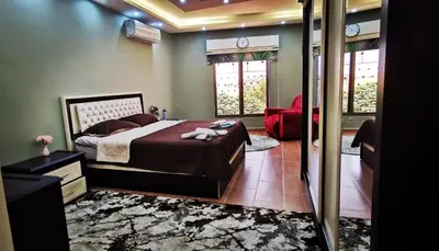 a bedroom with a large bed and a red chair at شقة كبيرة مميزة للعائلات -مدخل مستقل in Amman