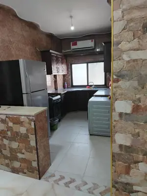 a kitchen with a refrigerator and a stone wall at الشقة الفاخرة الحديثة in Amman
