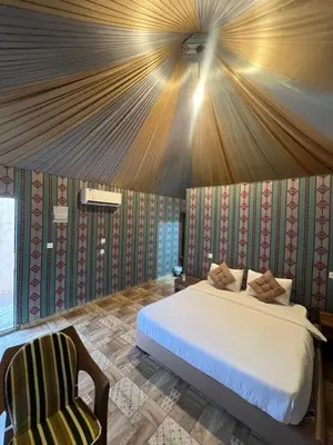 a bedroom with a large bed and a chair at RUM PILLARS REST houstl in Wadi Rum
