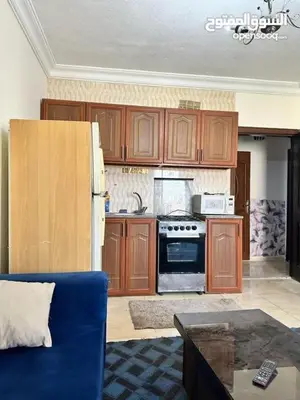 a kitchen with wooden cabinets and a blue couch at studio al jubiha 1 استوديو الجبيهة in Amman
