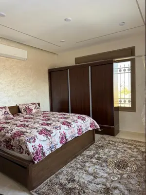 a bedroom with a large bed with a wooden headboard at شالية جوهرة جراسيا Jewel of Gracia Chalet in Jerash