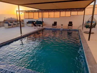 a swimming pool in a house with chairs around it at شاليه ومزرعة طبقة فحل Chalet Pella