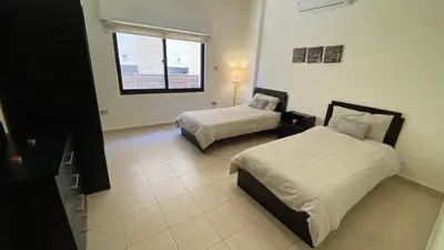 a bedroom with two beds and a window at Dair Ghbar Apartment in Amman