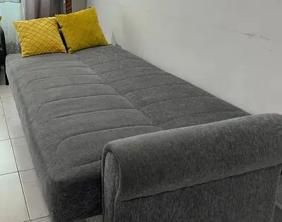 a gray couch with a yellow pillow on a wall at Central affordable studio in Amman