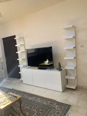 a living room with a tv and a white entertainment center at Affordable Furnished 2BR for Rent in Amman