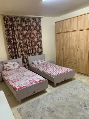 a bedroom with two beds and a cabinet at Affordable Furnished 2BR for Rent in Amman