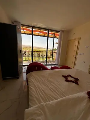a bedroom with a bed and a large window at شاليه هاف مليون الرامة in Al Mazār