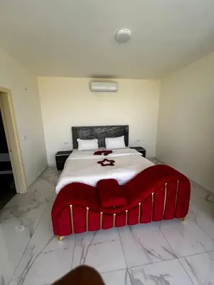 a bedroom with a large bed with a red blanket at شاليه هاف مليون الرامة in Al Mazār
