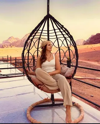 a woman sitting in a swing in the desert at LUXURY camp in Disah