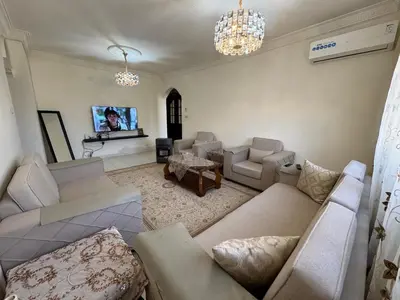 a living room with couches and a flat screen tv at Comfort Apartment in Amman
