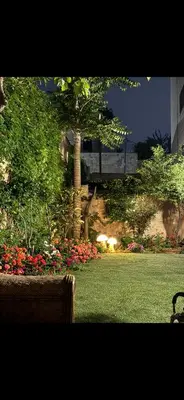a garden with flowers and a tree and a building at Comfort Apartment in Amman