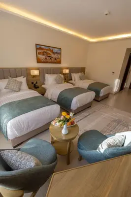 a hotel room with three beds and two chairs at Petra Legacy Luxury in Petra