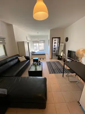 a living room with a black couch and a table at Studio for Rent in Jabal Alweibdeh-Amman - Jordan in Amman
