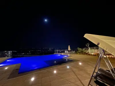 a swimming pool at night with the moon in the sky at sofia Farm in Al Salt