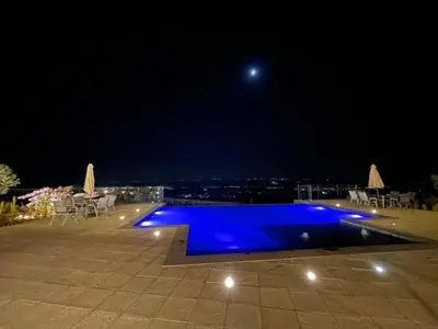 a blue swimming pool at night with a view at sofia Farm in Al Salt