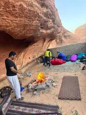 a group of people sitting around a camp fire at cave under the stars in Wadi Rum
