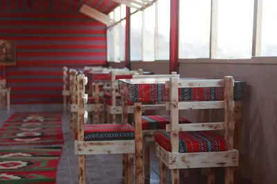 a row of wooden chairs with red cushions on them at Petra Brothers in Petra