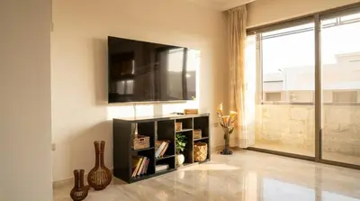 a living room with a television on a wall at Cozy & Spacious 3 En-Suite Bedroom Apartment in Amman