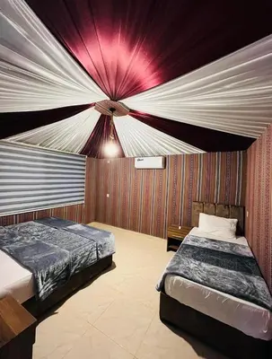 a bedroom with two beds and a red and white ceiling at Desert yanal wadi rum in Disah