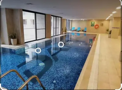 a swimming pool with a blue floor in a building at Sunny Duplex for rent in Abdali in Amman