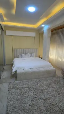 a bedroom with a large white bed and a rug at شقق-روف للايجار اليومي والاسبوعي in Al Qarţū‘īyah