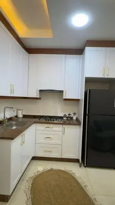 a kitchen with white cabinets and a black refrigerator at شقق-روف للايجار اليومي والاسبوعي in Al Qarţū‘īyah