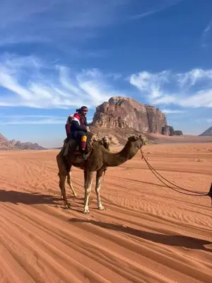 two people riding on a camel in the desert at Mountain Stars Camp in Wadi Rum