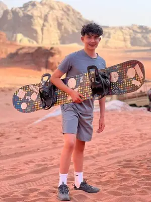 a young man holding a skateboard in the desert at Mountain Stars Camp in Wadi Rum