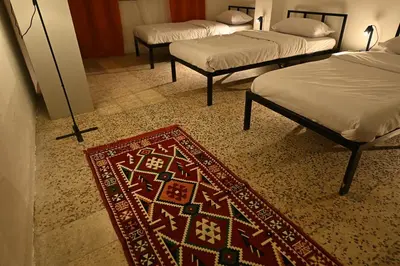 a room with three beds and a rug on the floor at AL Majd hostel in Amman