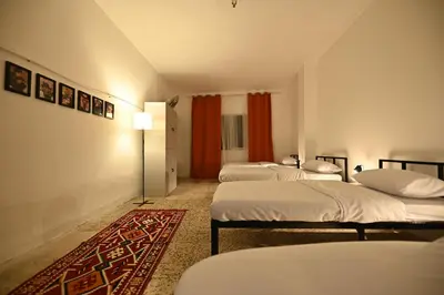 a room with four beds and a rug at AL Majd hostel in Amman