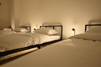 two beds in a room with white sheets and pillows at AL Majd hostel in Amman