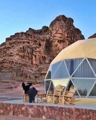 a woman sitting in a chair in front of a tent at Wadi Rum Bubbles Luxury Camp in Wadi Rum