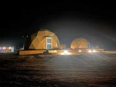 two dome shaped buildings at night with lights at Aurora Luxury Wadi Rum in Wadi Rum